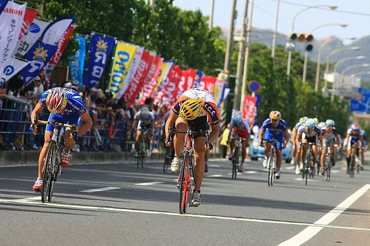 中鶴友樹（TEAM KIDS）と阿部紘太（法政大学サイクリング同好会）が自転車を投げあう