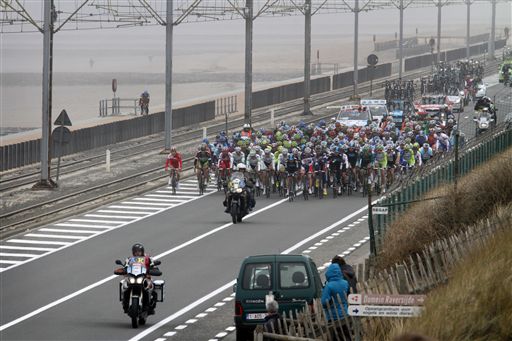 強風の吹く海沿いの道を行くプロトン