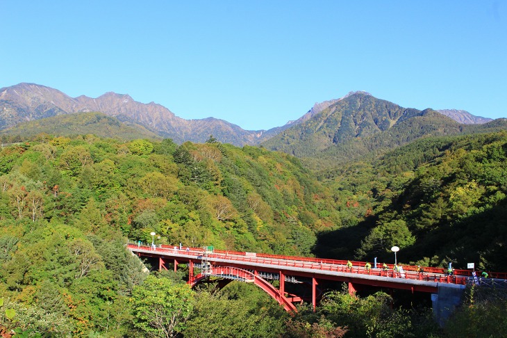 谷にかかった真っ赤な東沢大橋を渡る