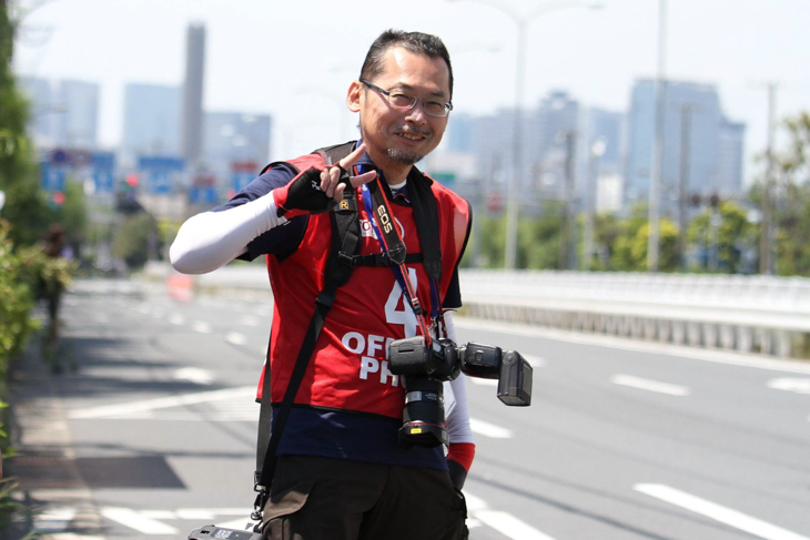 ツアー・オブ・ジャパン2017東京ステージで撮影中の高木秀彰さん。カメラを向けるとピースで応える