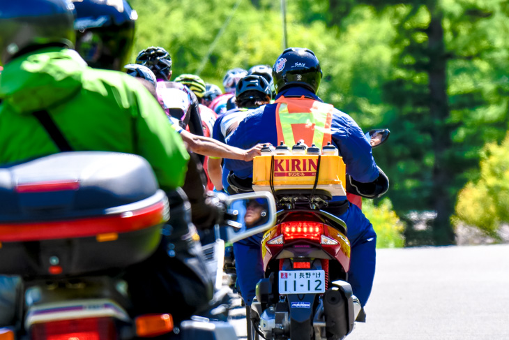 バイクからボトルを補給するために手を伸ばす選手