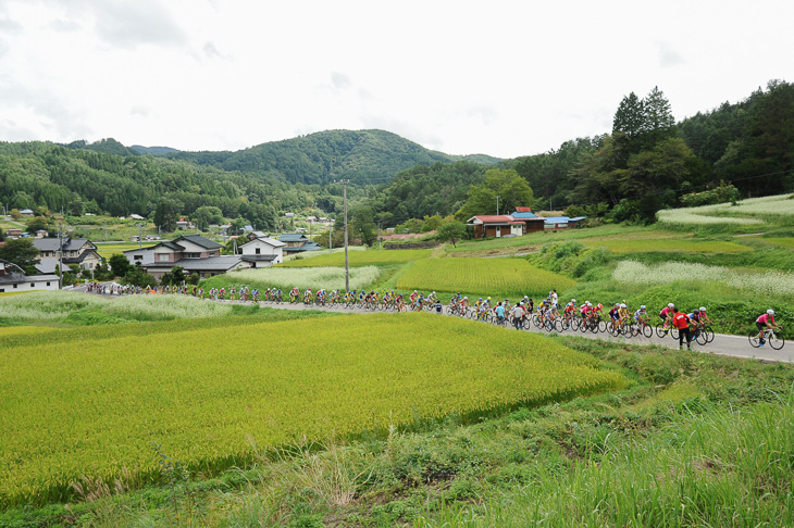 美麻地区の集落の中を一列で進む集団