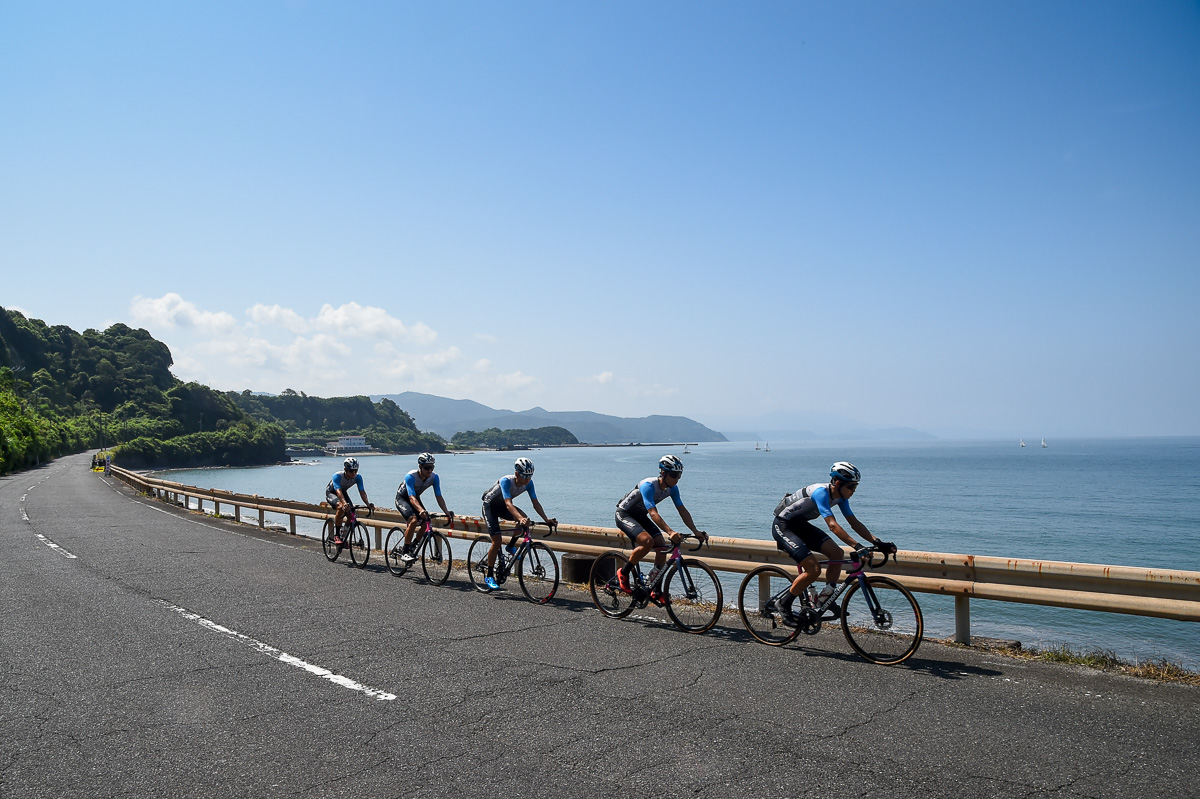 青空が広がった鹿児島湾に沿って走るシエルブルー鹿屋のメンバー