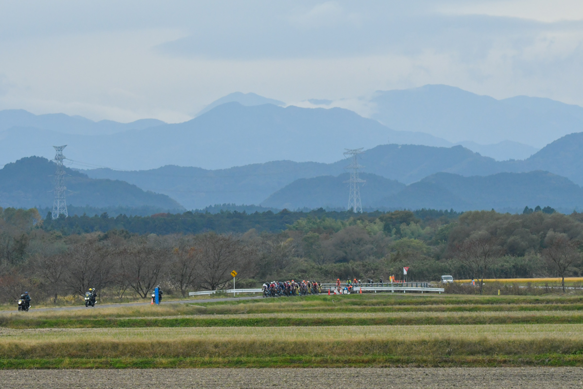 稲刈りを終えた田園風景の中をプロトンが進む